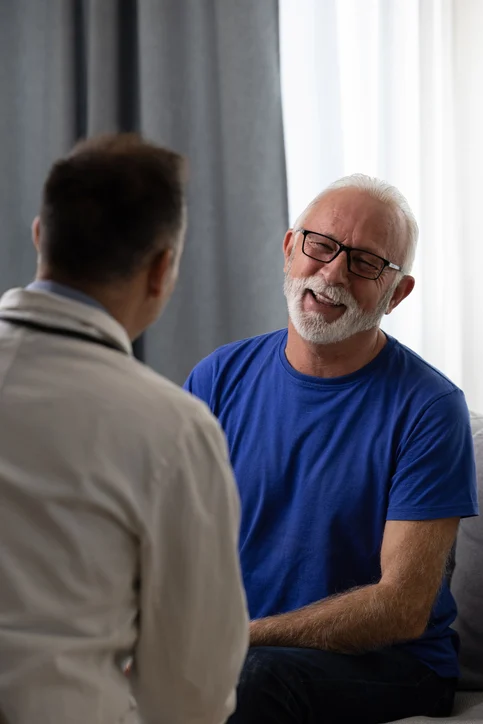 Healthy smiling senior patient feeling cheerful about good news at medical consultation. Happy eldelrly man talking to a doctor at appointment.
